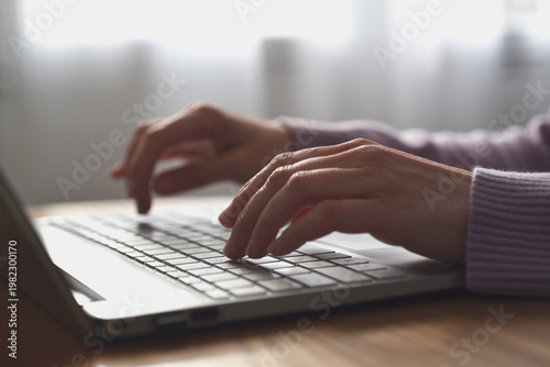 Woman typing on computer keyboard at home