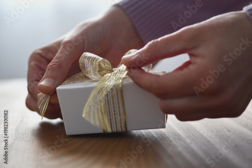 Woman holding little gift box with ribbon opening or preparing gift