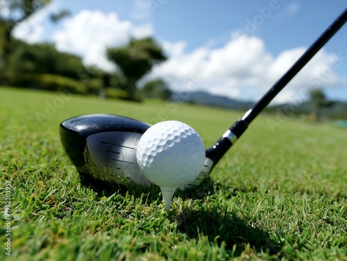 Golf ball on white tee with driver on green grass