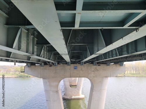 Photography Looking up at the architectural structure of the pier underneath Gwangjingyo Bridge in Seoul, South Korea, with the Han River in the background