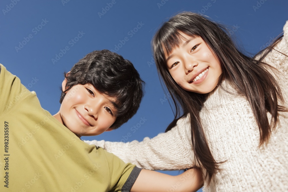 Fototapeta premium Two children embracing under clear blue sky outdoors