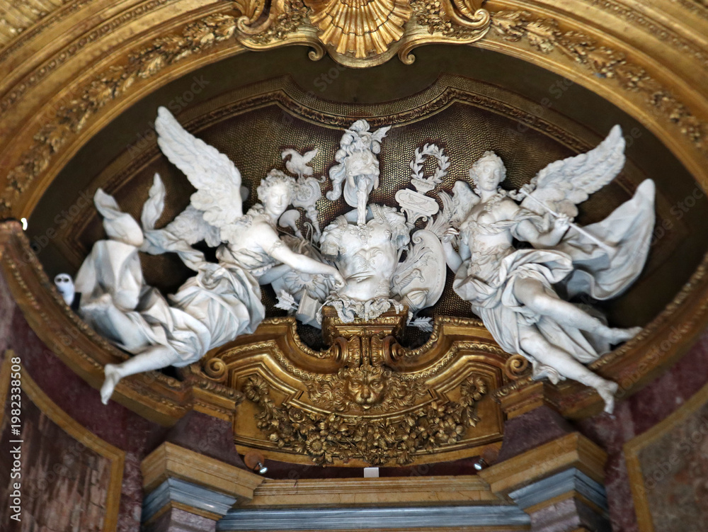 Fototapeta premium Sculture in marmo bianco raffiguranti angeli alati in stile barocco all'interno di una nicchia monumentale con decorazioni e rilievi dorati
