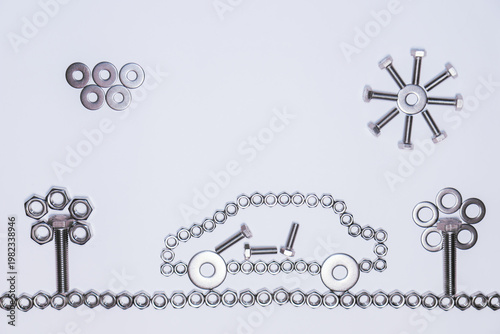 An artistic composition using nuts, washers, and bolts to form a car. The central structure is elongated and symmetrical. To the right appears a sun made of metal pieces,