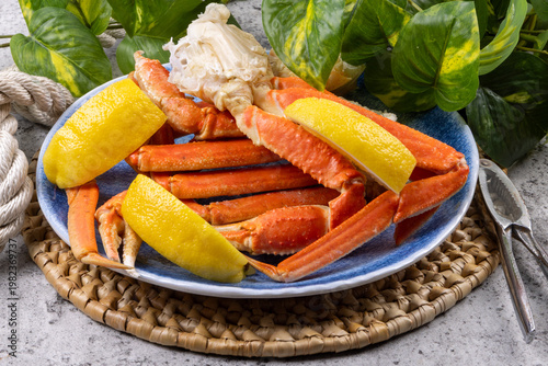 Cooked snow crab leg clusters on a dinner plate with lemon wedges and a lobster cracker