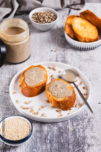 Toast with sesame and sunflower tahini on a plate on the table vertical view