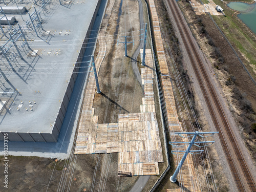 Bild auf Leinwand Aerial view of timber construction mats forming temporary access roads for power line installation beside substation, transmission towers, and railway corridor