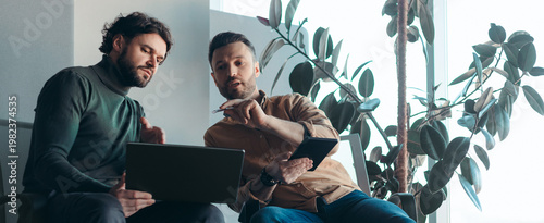 Fotografie Two men sit next to each other in a modern office