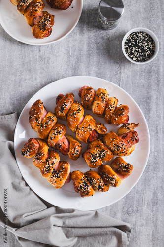 Homemade sausages in sesame dough on a plate on the table top and vertical view