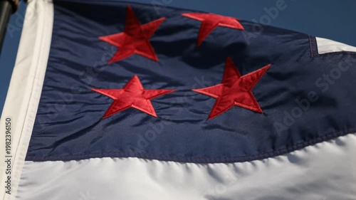 Close-up of a waving flag with three red stars on a blue background and white stripe.