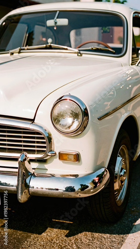 A vintage white sedan is bathed in warm sunlight, its chrome details gleaming with a sense of nostalgia and classic automotive design.