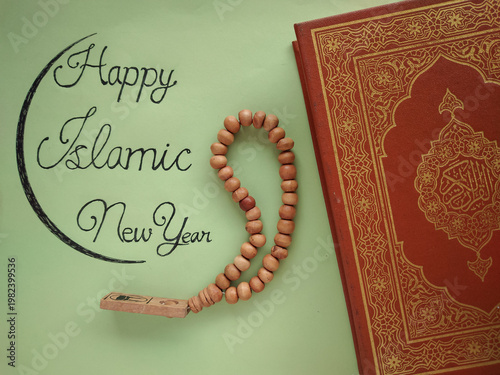 Happy Islamic New Year Greeting with Holy Quran Book, Wooden Prayer Beads and Handwritten Calligraphy on Green Background – Hijri New Year Celebration Concept