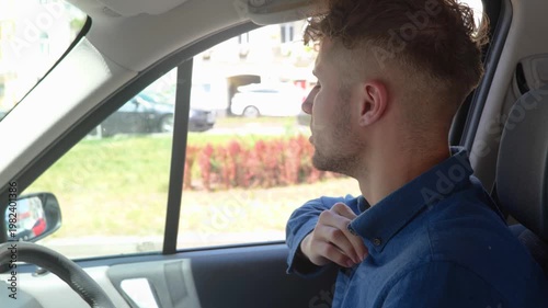 Exhausted man sitting inside car hot weather while looking on the road in the city. Right hand drive car. Lifestyle, travel, transport concept. Real time