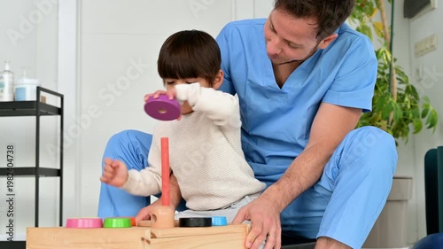 Child with disability performing motor skills exercises with physiotherapist using educational game. Pediatric rehabilitation, coordination development, therapy and healthcare concept. High quality 4k