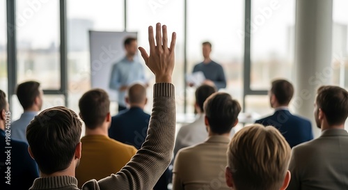 Audience member raises hand during business presentation with speakers.