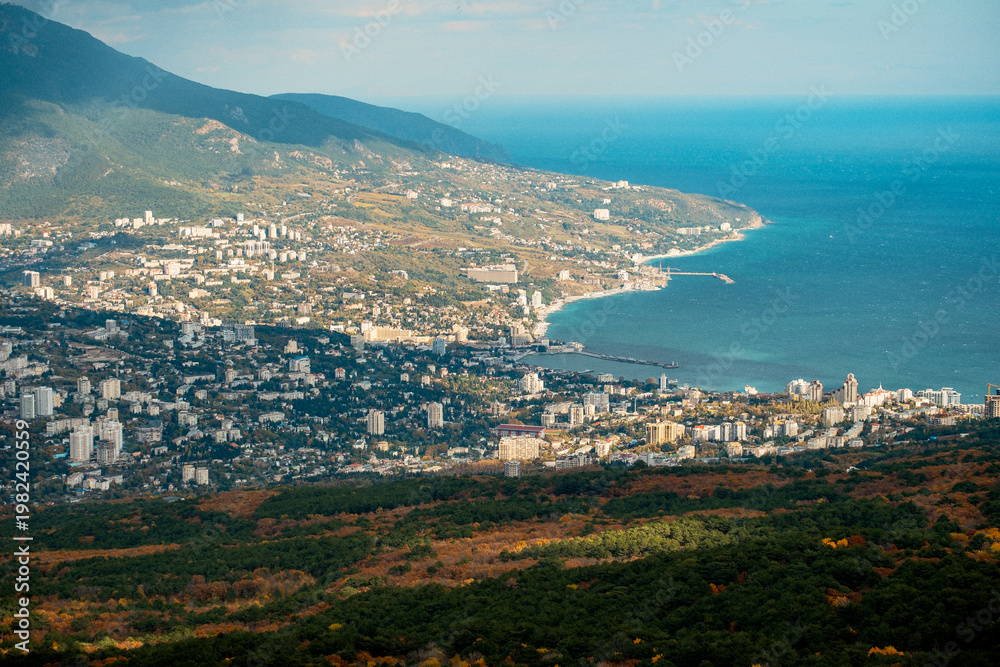 Fototapeta premium Elevated View Of Bustling Shoreline And Mountains. Aerial Shot Of Lively Coastal Town With Bay And Hills