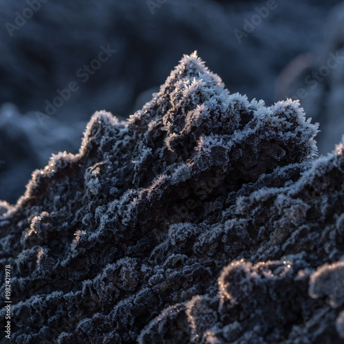 Close Up Macro of Volcanic Rock Texture Covered with Morning Frost Ice Crystals, Dramatic Side Lighting on Dark Lava Stone Surface