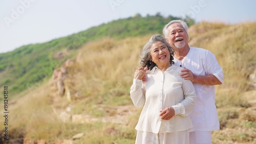 Asian senior couple embracing on seaside cliff, elderly enjoying romantic moment together, happy retirement lifestyle, love and relationship in old age, travel nature outdoor activity by the ocean