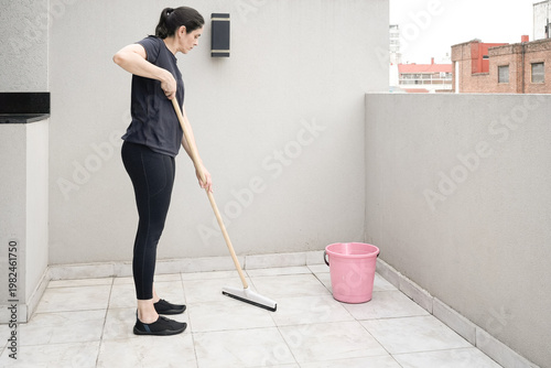 Quadro su tela Woman cleaning terrace floor with squeegee and bucket