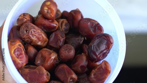 White bowl filled with dark brown dried dates fruit. Perfect for food blogs, recipes, healthy eating articles, and ramadanthemed designs.