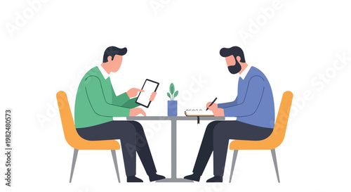 Two professional men sit at a table collaborating; one points at a digital tablet while the other takes notes in a notebook during a meeting.