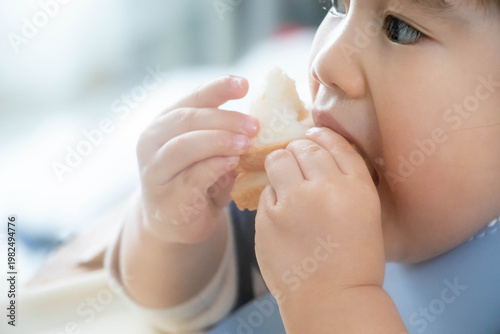 Foto パンを食べる幼児のクローズアップ（手づかみ食べ・日常の食事風景）