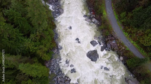 Aerial drone overhead shot of a whitewater river flowing aggressively in a lush forest