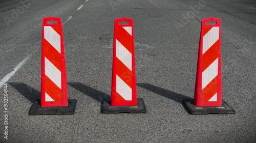 Three large pylons on a multilane road blocking a turning lane on a sunny day