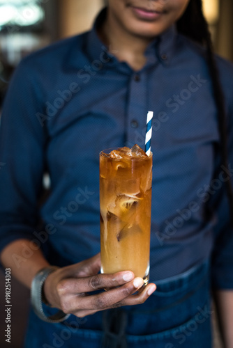 Person in Blue Shirt Holding Iced Coffee with Milk