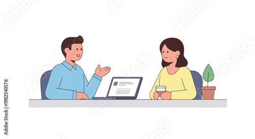 A man in a blue shirt talks to a woman in a yellow top while sitting at a table with a laptop and a potted plant in a workspace.