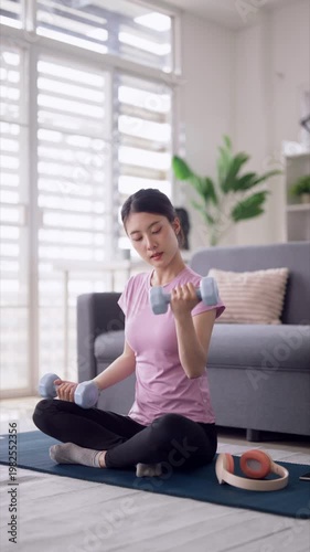 Asian adult woman home workout dumbbell exercises mat for fitness health wellness in modern apartment living room focused on personal training