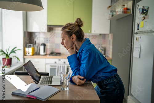 Thoughtful mature woman engaged in learning process online on laptop at home, female watching professional speakers live streams and podcasts, lady changing career direction, getting new knowledge.
