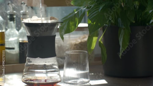 Hot water pouring into paper filter dripper during manual coffee brewing at home. Concept of pour over preparation morning ritual and specialty coffee lifestyle.