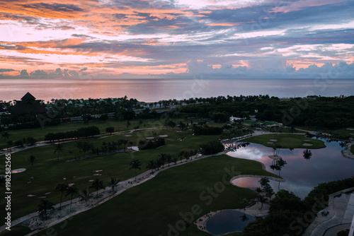 An enchanting sunset casts vibrant colors over a tropical golf course, enhancing the beauty of the natural surroundings and providing a sense of serenity and peace.