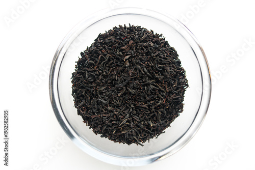 Top view of a clear glass bowl filled with dark, loose-leaf tea. Isolated on a white background.