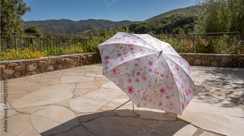 Floral umbrella stands on a stone patio with a mountain view in the background on a sunny day