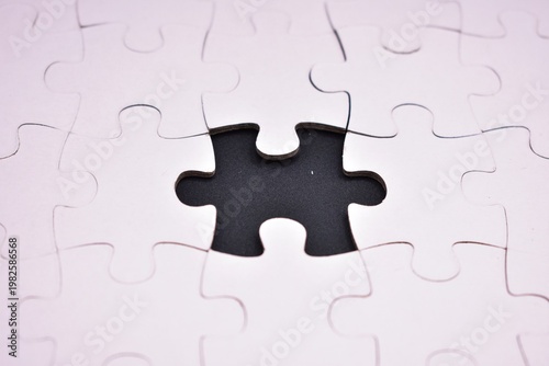 Фотография An incomplete white jigsaw puzzle featuring a single central void, symbolizing a missing element, problem-solving, or an unfinished task