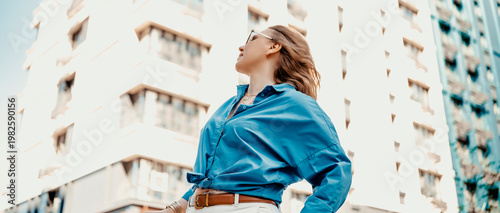 Woman in blue shirt on bright overexposed city background. Minimalism and high key photography style.