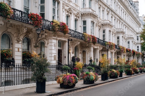 A picturesque street in London showcases elegant white townhouses adorned with vibrant floral displays, creating a charming and colorful urban scene.