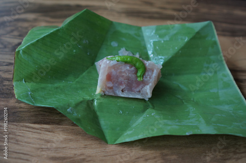 Close up of an authentic Thai Naem Moo or fermented pork sausage wrapped in banana leaf