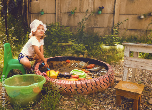 Fotografie Child girl playing with fun on the sand pit with toys, basin with water