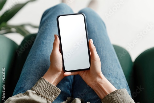 A person casually holds a modern smartphone in their lap, showcasing a blank screen and a relaxed, everyday moment.