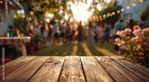 A warm, inviting outdoor gathering is softly blurred in the background, with a rustic wooden surface taking center stage, suggesting a space for display or presentation.