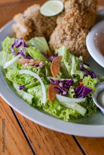 Close up of fresh salad with lettuce, tomato, cabbage and fried chicken. Detailed texture and natural lighting, healthy food concept