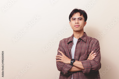 Professional portrait of successful leader. Confident young Asian man standing with crossed arms on isolated background.