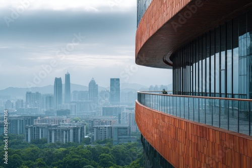 A modern building with a curved facade overlooks a sprawling cityscape under a cloudy sky.