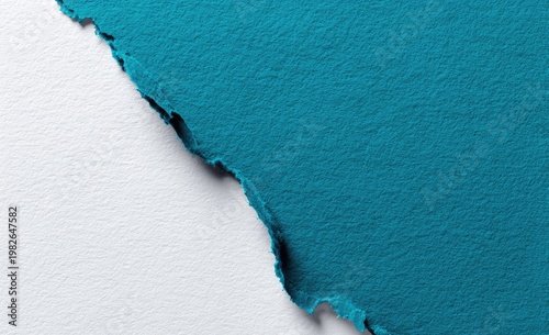 A close-up shot showcases a torn edge between textured turquoise paper and a clean white surface, creating a dynamic contrast in color and texture.