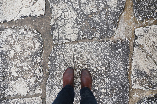Person stands on cracked stone pavement underfoot