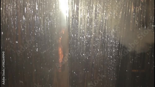 Woman in red dress standing behind blue tinsel with a melancholic expression
