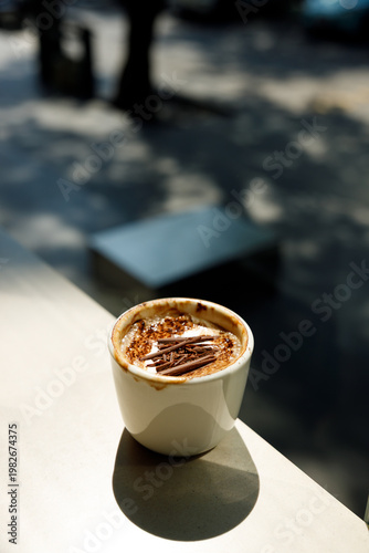 Cup of hot milk latte coffee on table by the window.