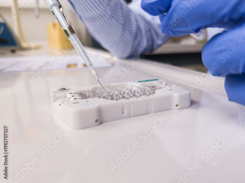 Brussels, Belgium. Scientist pipetting sample into ddPCR cartridge for DNA and GMO analysis in laboratory